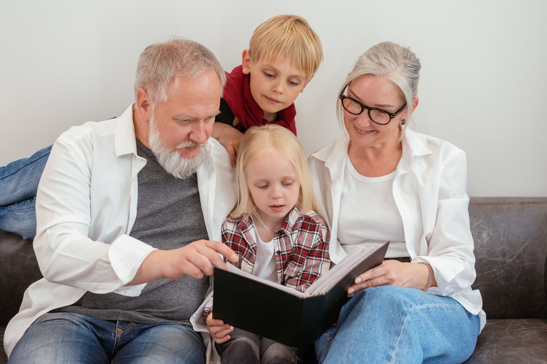Grandparents and grandchildren looking through a family photo album together