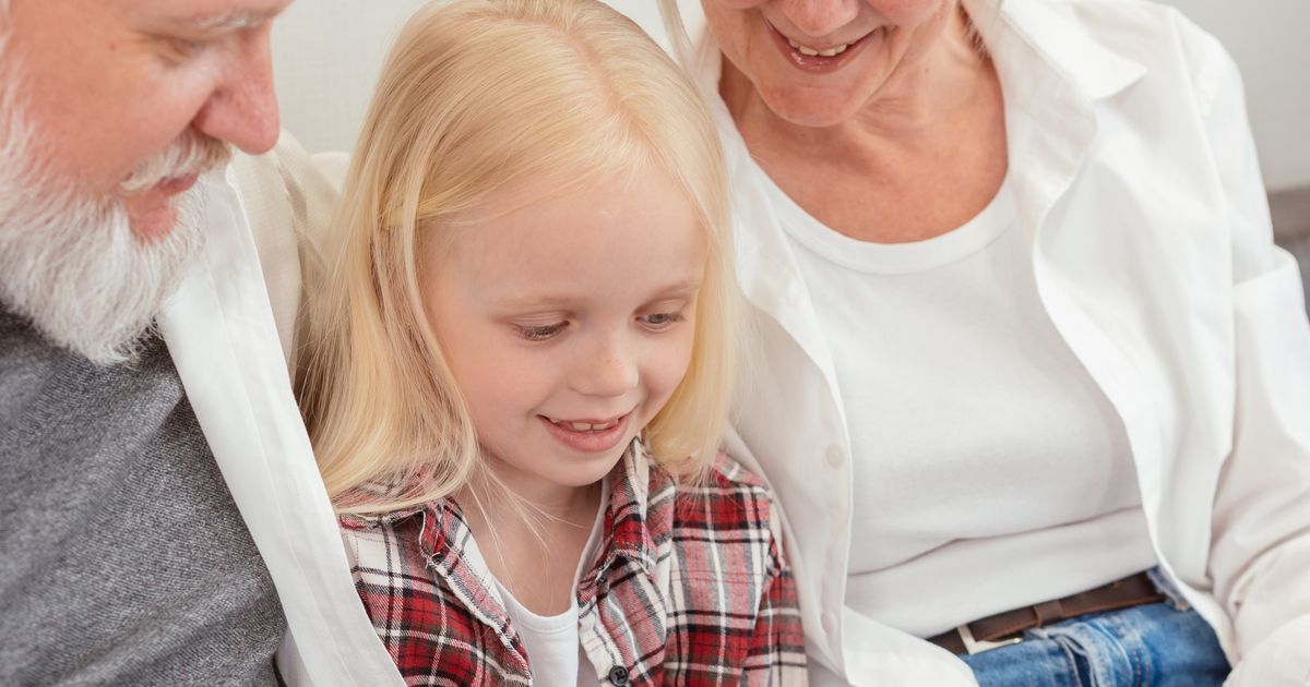 Grandparents and their granddaughter smiling over family photos