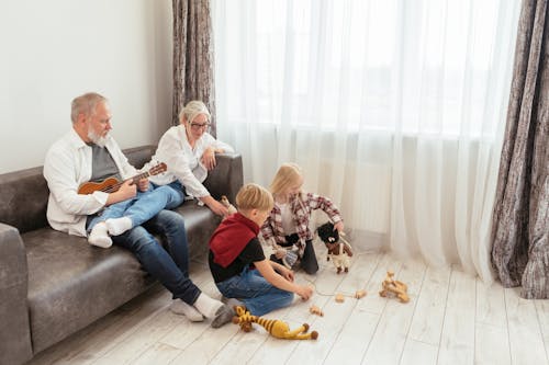Free Woman in White Long Sleeve Shirt Sitting on Couch With Children Stock Photo