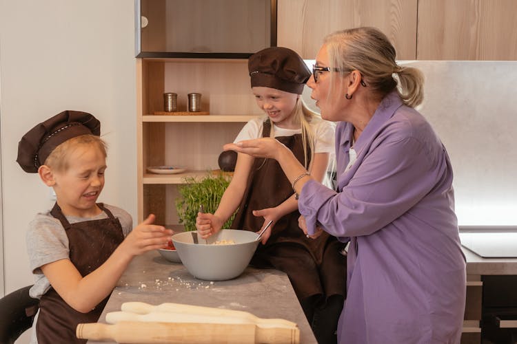 Elderly Woman In Purple Shirt Having Fun While Cooking With Grandchildren