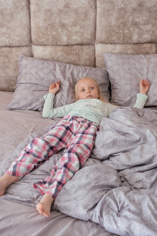 Free Little Girl Lying in Bed Wearing Pyjamas Stock Photo