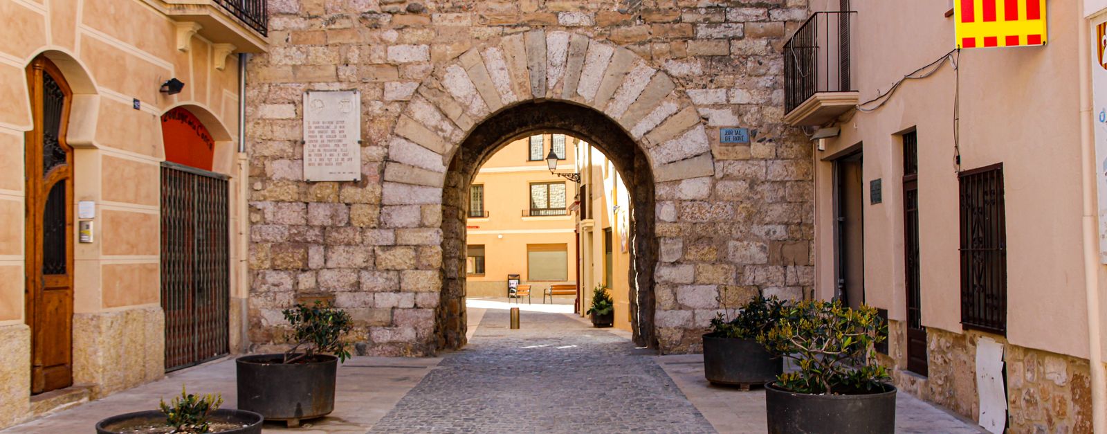 Charming cobblestone street with historic stone archway in Montblanc, Spain.