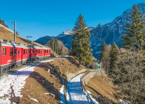 A picturesque train journey through snow-capped mountains and evergreen forests in Switzerland.