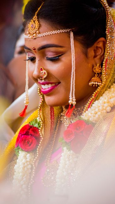Smiling bride adorned with traditional jewelry and flowers, showcasing cultural beauty.