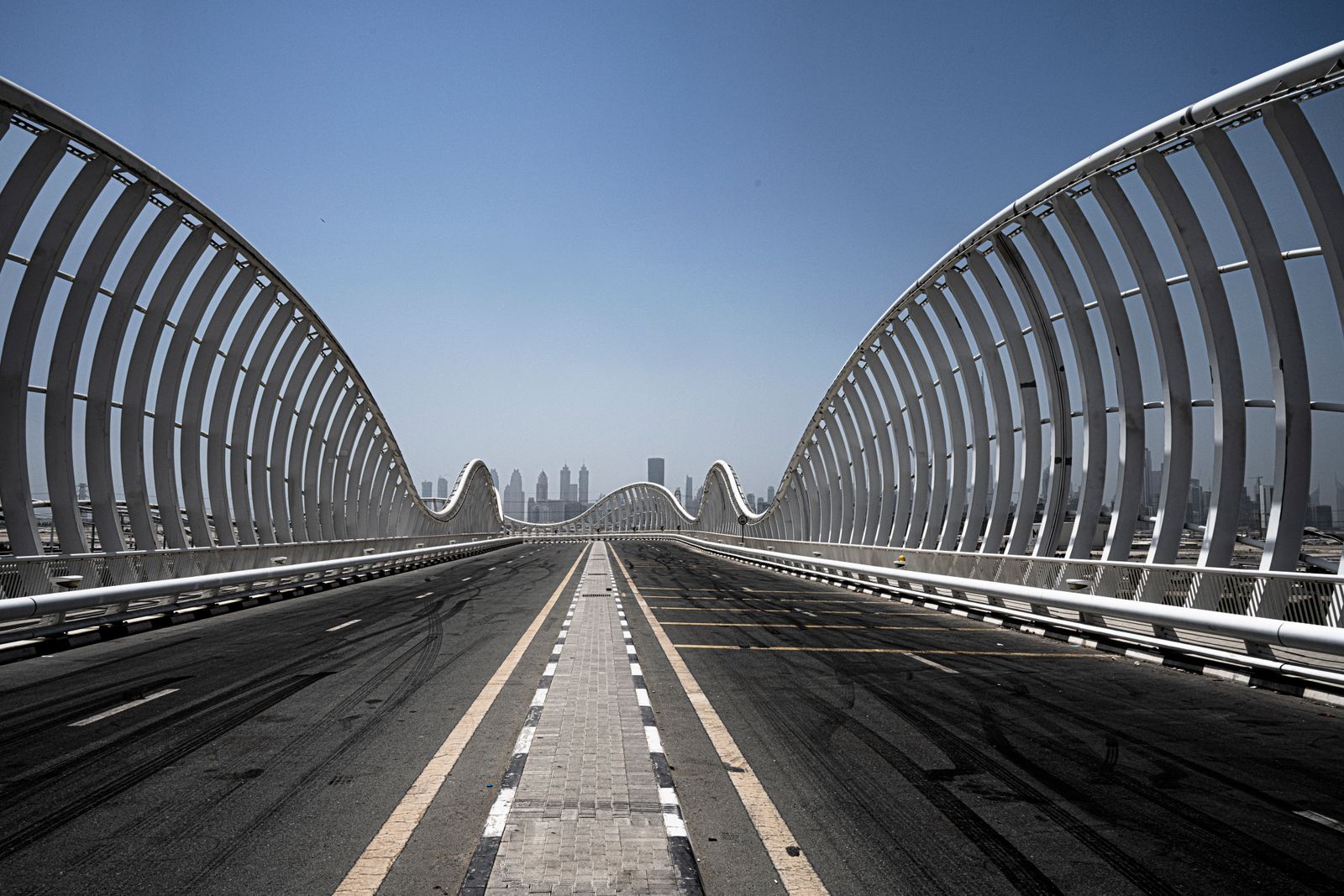 The wave-form Meydan Bridge on Al Meydan Road, the signature landmark at the entrance to the Meydan district within Mohammed Bin Rashid City, with the Dubai skyline on the horizon.