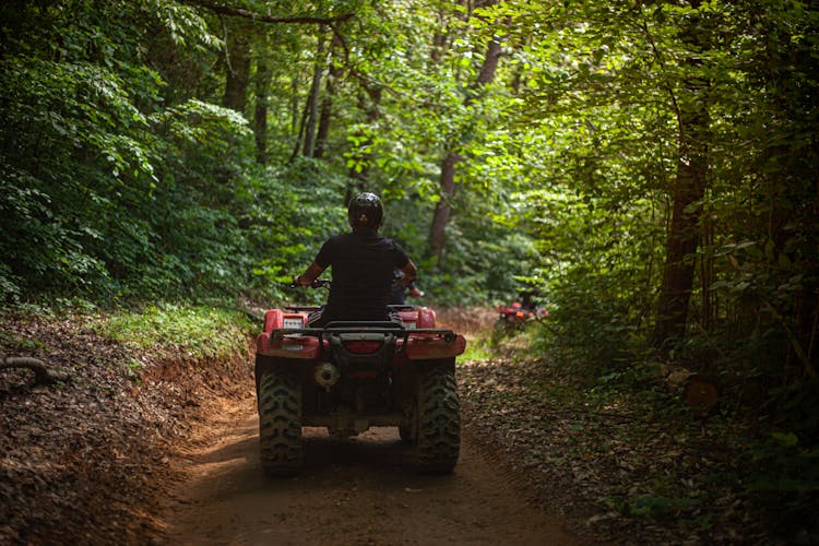 A Man Riding An All Terrain Vehicle In The Forest