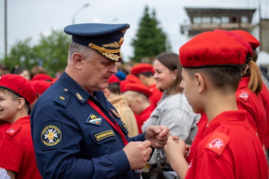A military officer engages with youth cadets in uniform at an outdoor event.