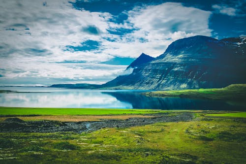 бесплатная Спокойный водоем возле Черной горы в окружении зеленой травы Стоковое фото