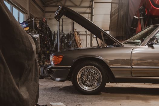 A classic car with an open hood in a well-equipped garage. Captured in Poznań, Poland.