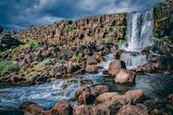 瀑布从长满青苔的岩石上倾泻而下，四周环绕着崎岖的悬崖与郁郁葱葱的绿植，风景十分优美