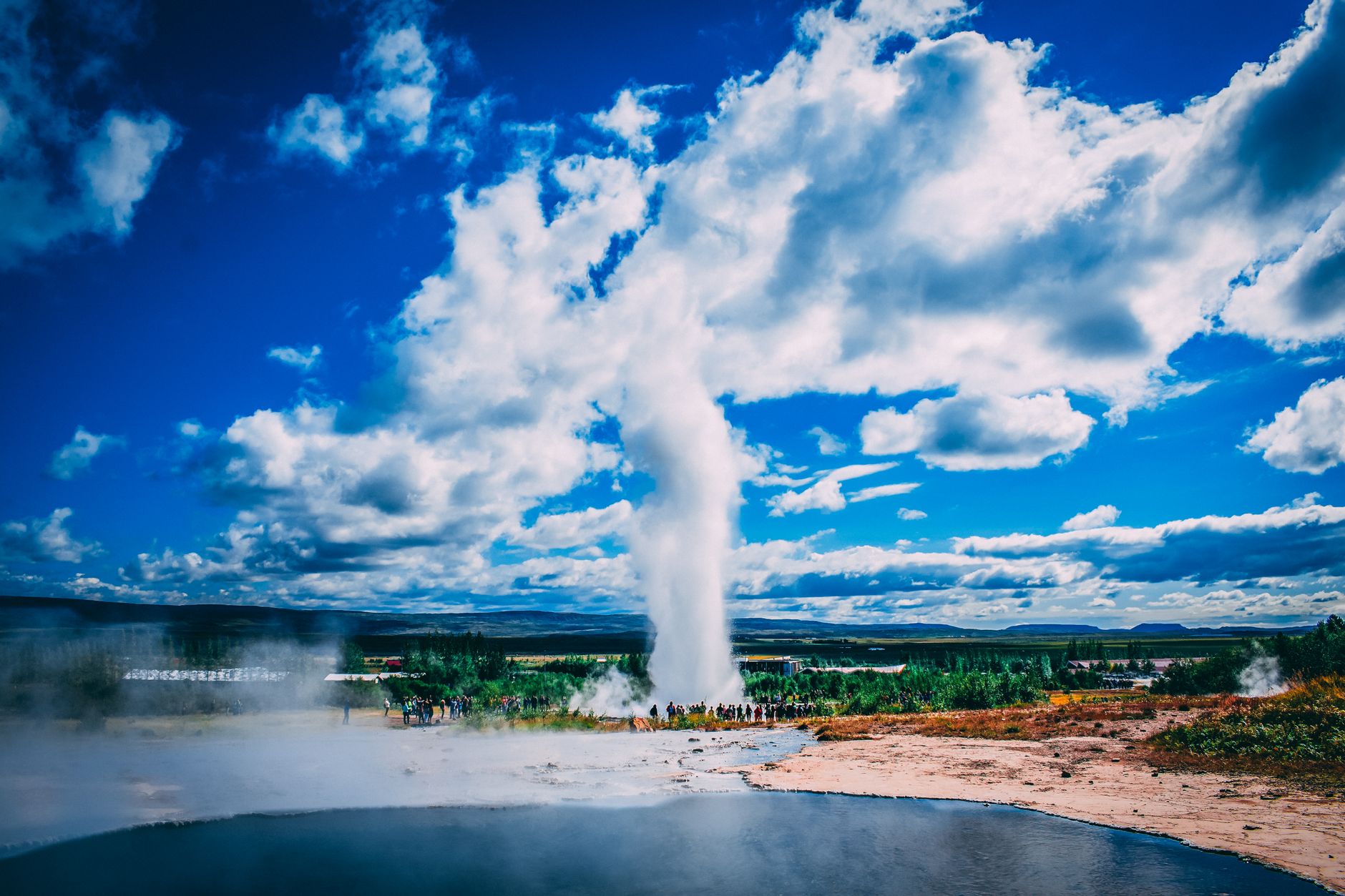 Steaming geyser erupting against blue sky on Iceland's Golden Circle