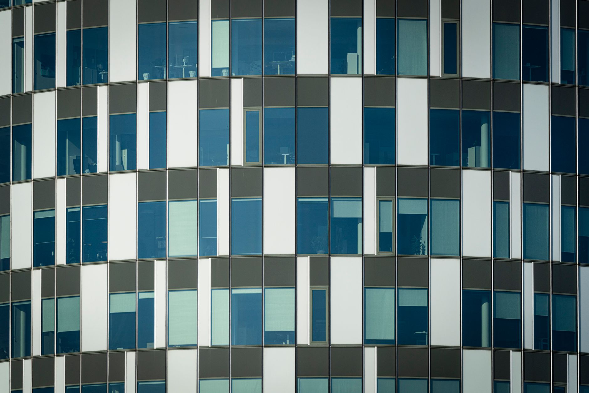 A modern office building with glass windows reflecting the sky.