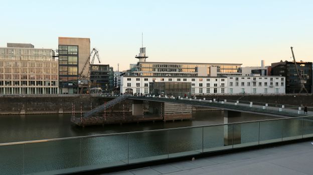 Modern buildings and footbridge over the river in Düsseldorf at twilight.