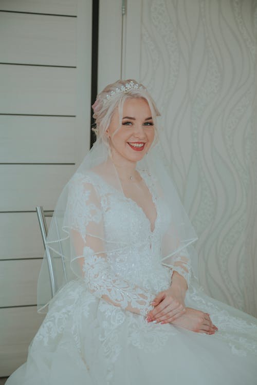 Woman in White Floral Wedding Dress Sitting on Silver Chair