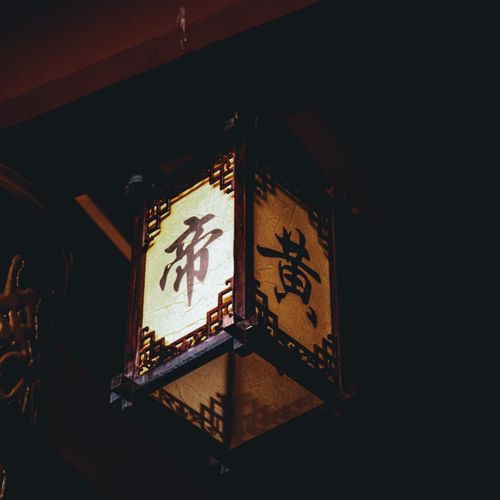Free A classic Asian lantern with intricate design hanging in a dim setting, casting warm light. Stock Photo