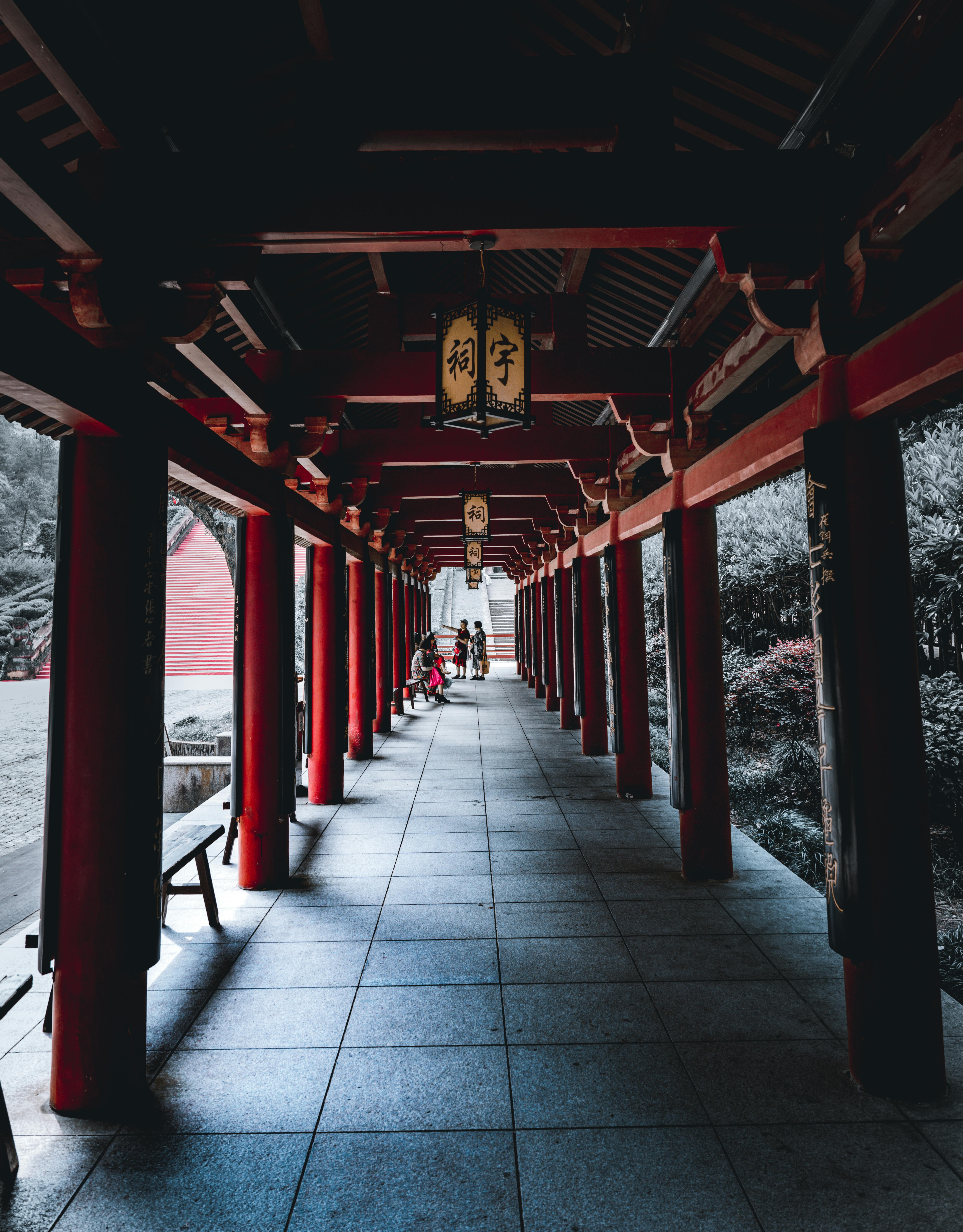 Tranquil passageway with red columns in traditional Asian architectural style.
