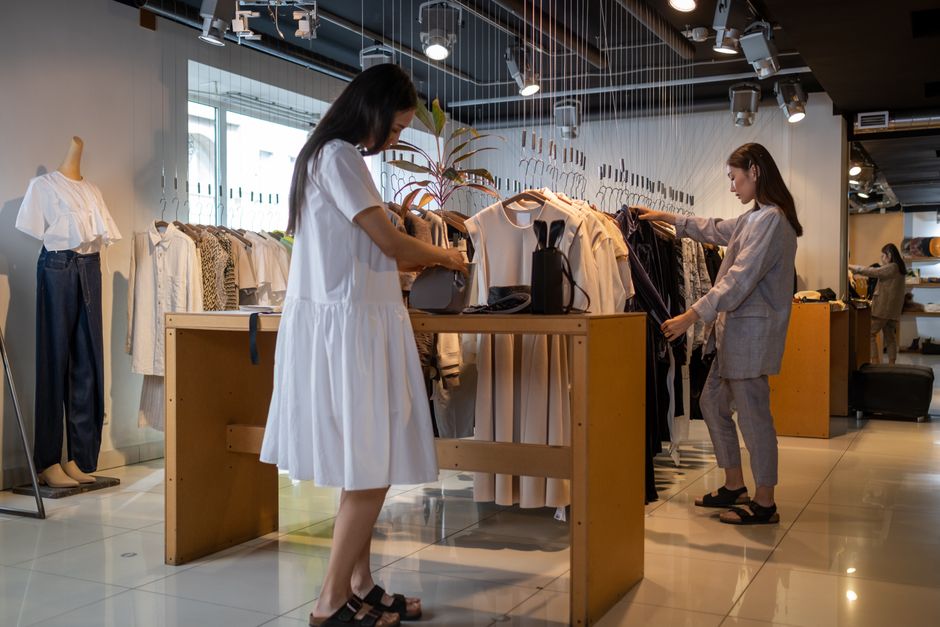 Two women browsing clothes in a modern indoor fashion store