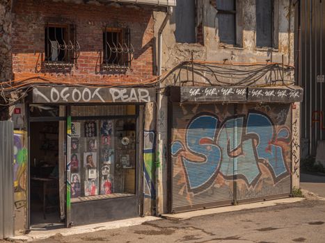 Rustic storefront with vibrant graffiti and worn brick facade. Urban decay meets street art.