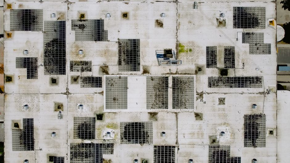 An industrial rooftop with solar panels, viewed from above, ideal for renewable energy concepts.