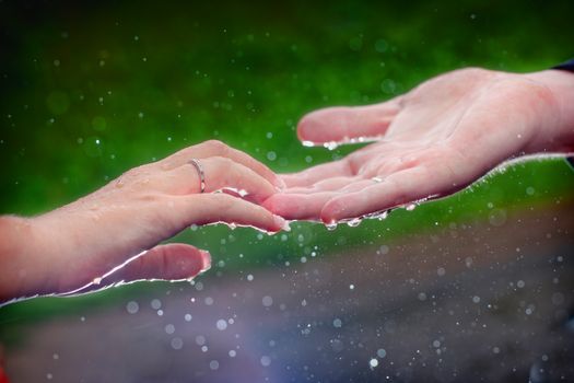 Close-up of a couple's hands touching in the rain, symbolizing love and connection.