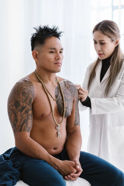 Free A professional acupuncturist treating a tattooed man for wellness in a clinic. Stock Photo