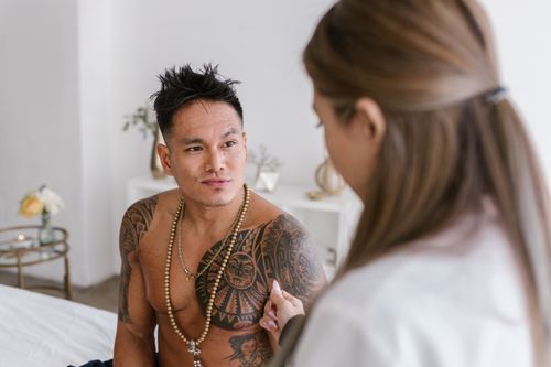 Free A tattooed man having a session with a therapist in a serene interior setting. Stock Photo