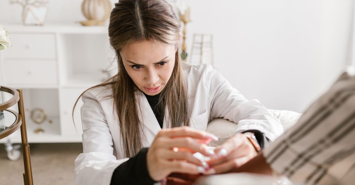 A concentrated female doctor providing medical care to a patient in a professional setting. Ideal for health and medical themes.