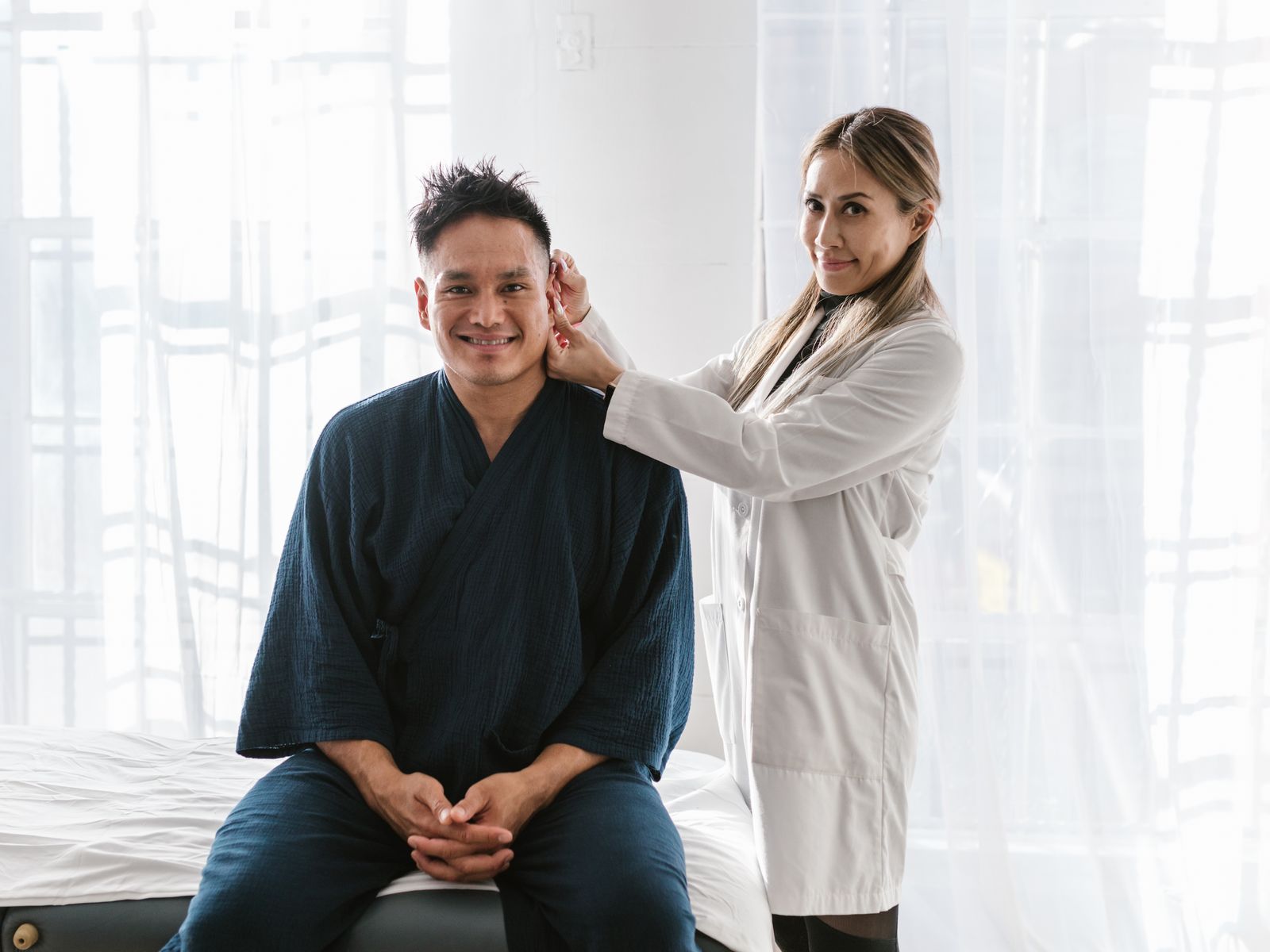 Doctor examining a smiling patient in a bright consultation room