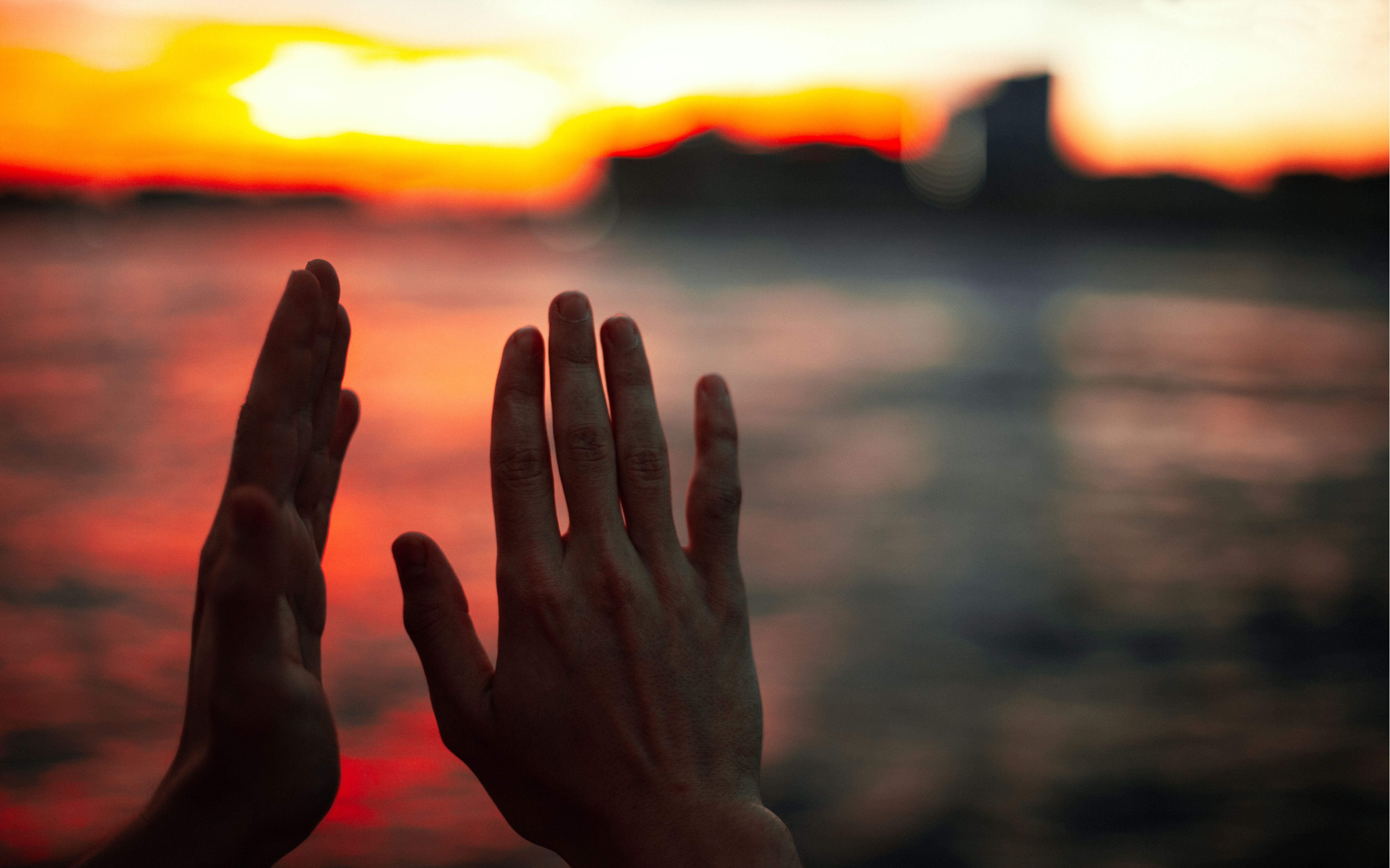 Open hands held out in the warm glow of a sunrise