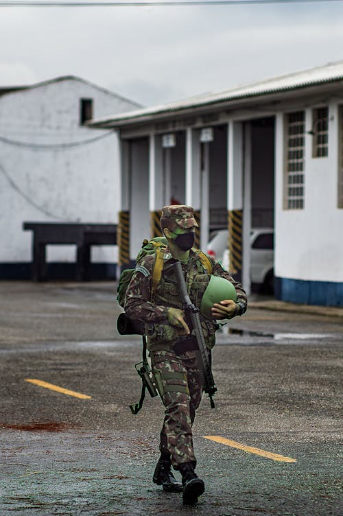 Free Man in Green and Black Camouflage Uniform Carrying Black and Brown Backpack Walking on Street during Stock Photo