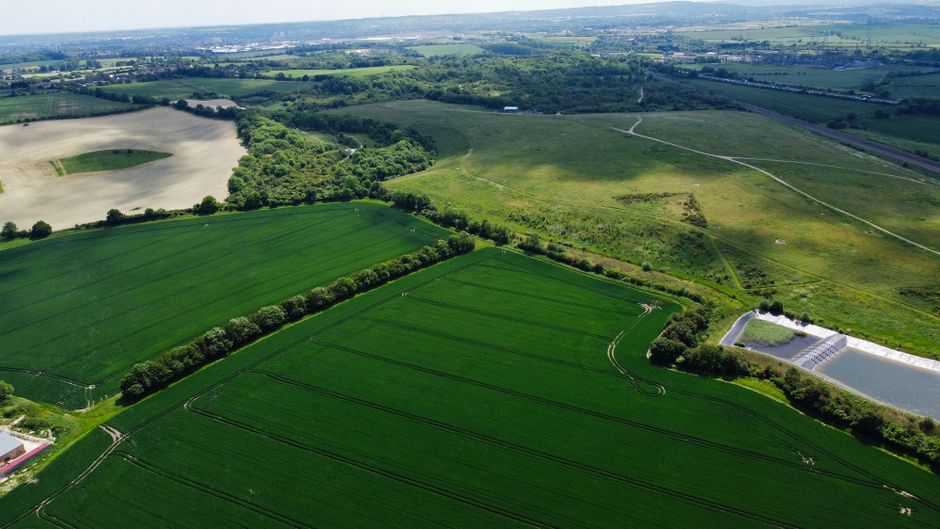 Aerial view of lush green farmland in Harlington, England, showcasing vast fields and countryside.