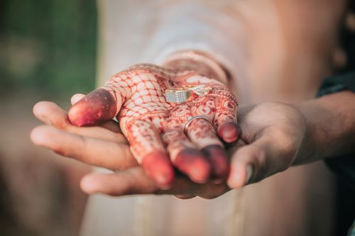 Free Close-up of hands with mehndi designs holding wedding rings, symbolizing engagement in India. Stock Photo