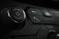 Detailed close-up of a vehicle's volume control knob and dashboard buttons indoors.