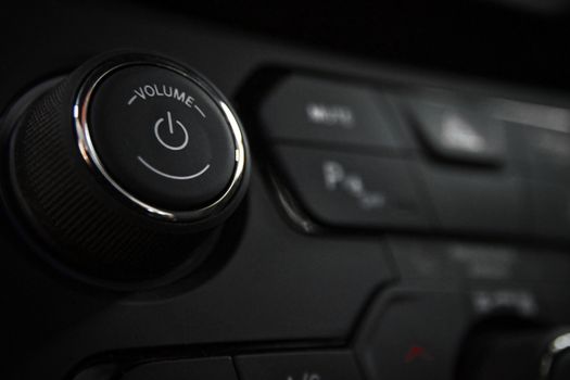 Detailed close-up of a vehicle's volume control knob and dashboard buttons indoors.