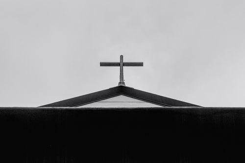 Free Black and white of from below of cross placed on roof of church against sky in daytime Stock Photo