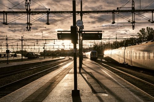 Free Silhouetted view of a train station with tracks during sunrise, featuring a striking silhouette and warm lighting. Stock Photo