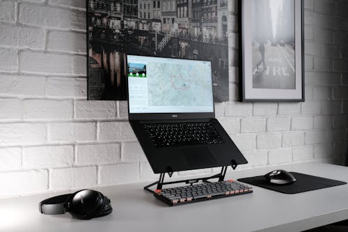 Free Close-Up Shot of a Laptop beside a Black Headphones on a White Desk Stock Photo