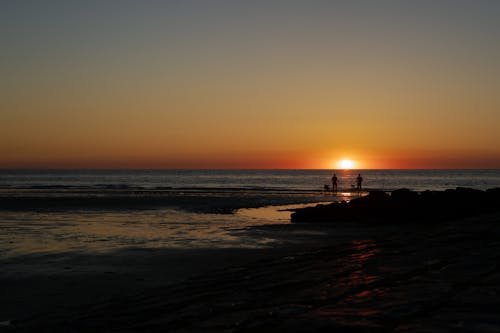A Silhouette of People on the Beach During Sunset