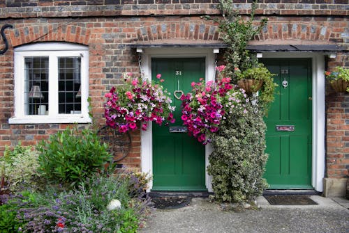 Free A Green Wooden Doors on a Brick House with Flowers and Plants Stock Photo