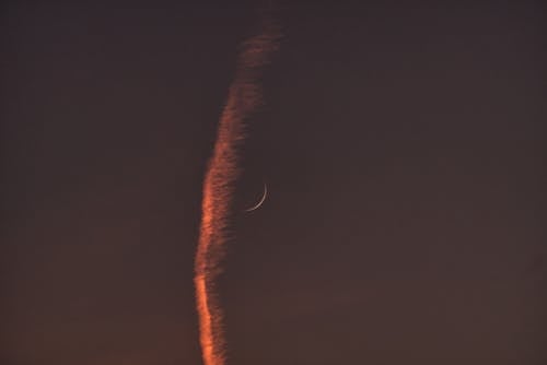 Free A Crescent Moon beside a Contrail in the Sky Stock Photo