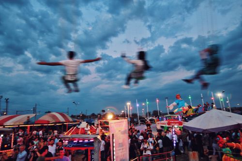 Free Dynamic evening scene capturing the excitement of an amusement park with rides and colorful lights. Stock Photo