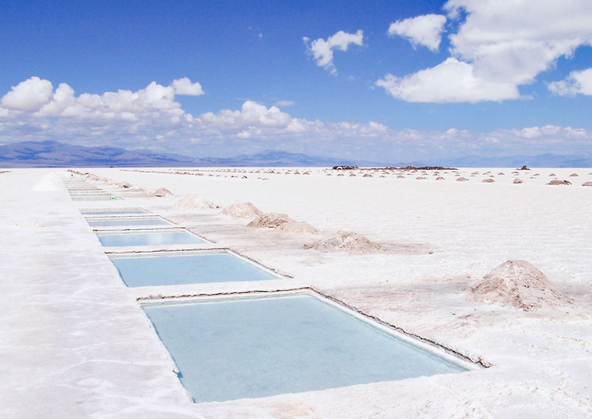Salinas con balsas de evaporación de agua azul y montones de sal bajo el cielo