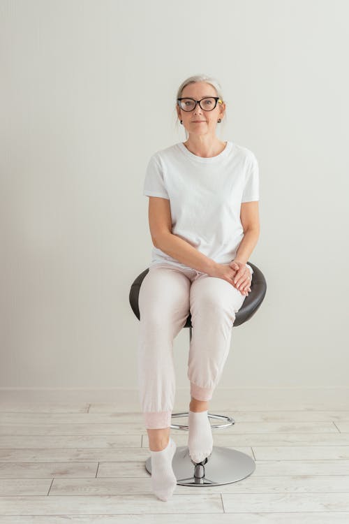An Elderly Woman in White Shirt Sitting while Wearing Eyeglasses