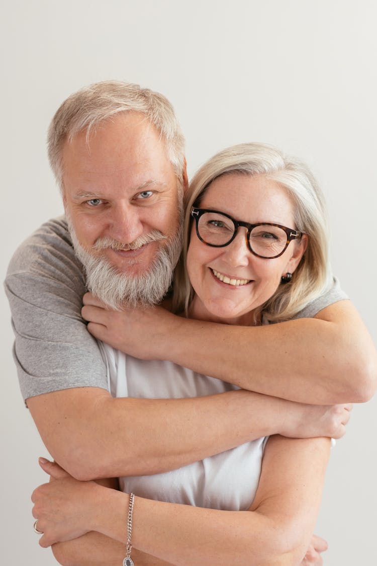 Close-Up Shot Of A Happy Elderly Couple Hugging While Looking At Camera