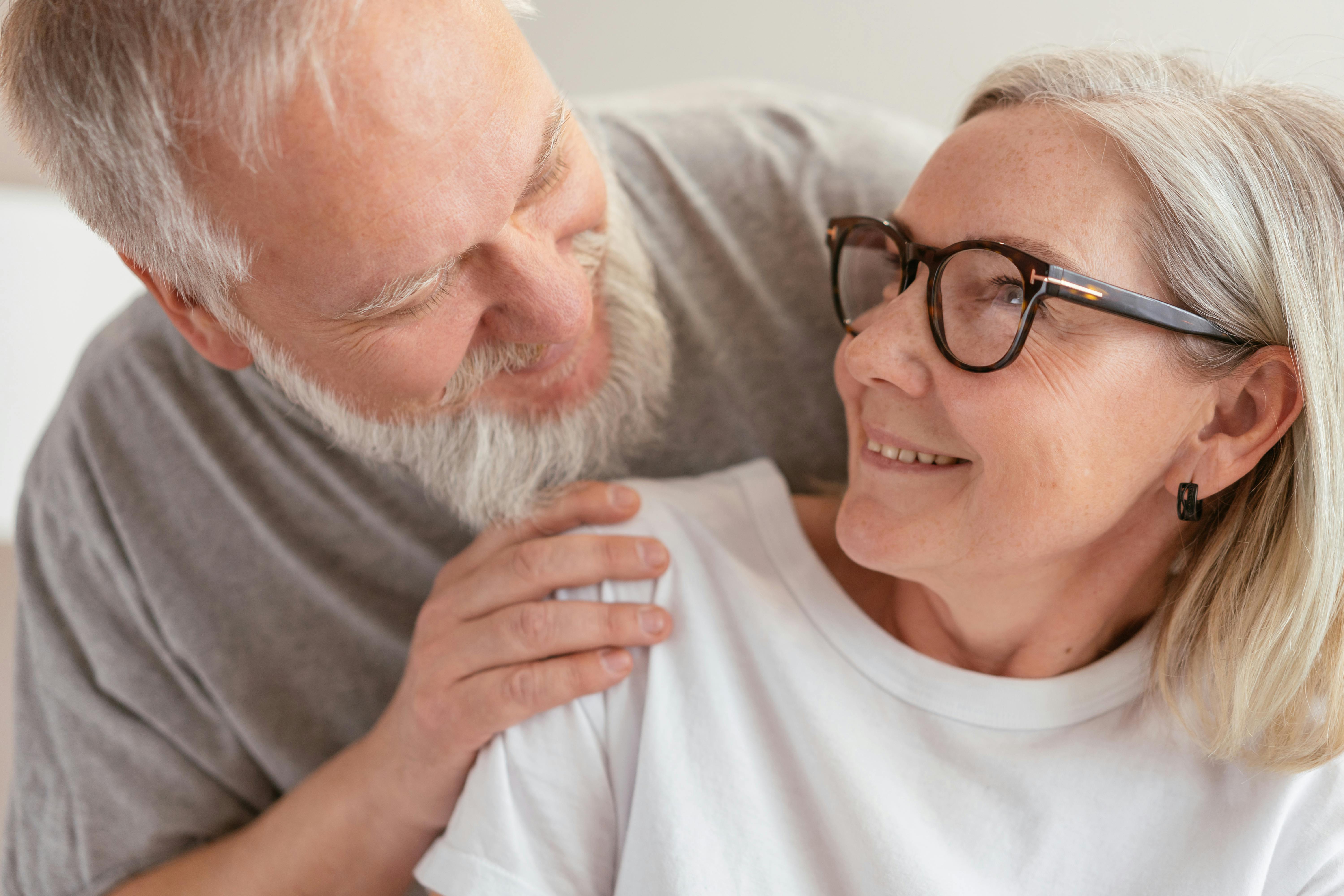 an elderly couple smiling while looking at each other