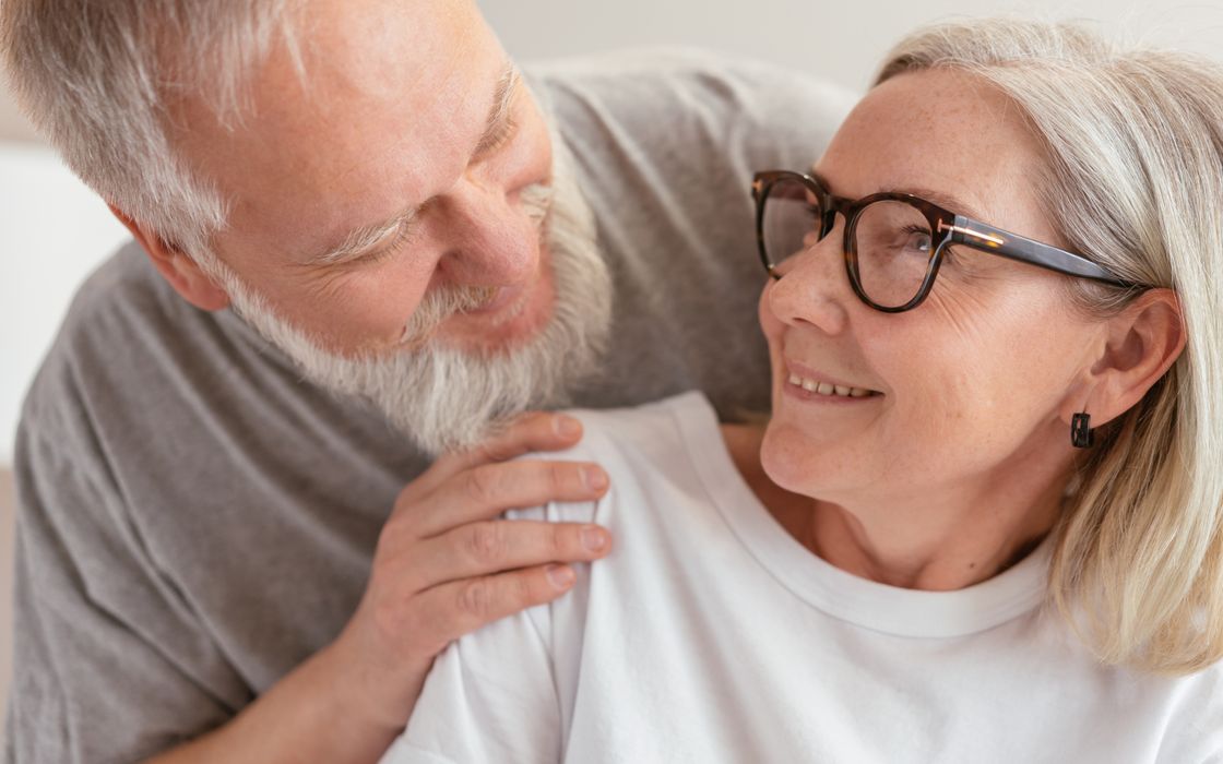 Senior couple smiling and enjoying each other's company indoors.