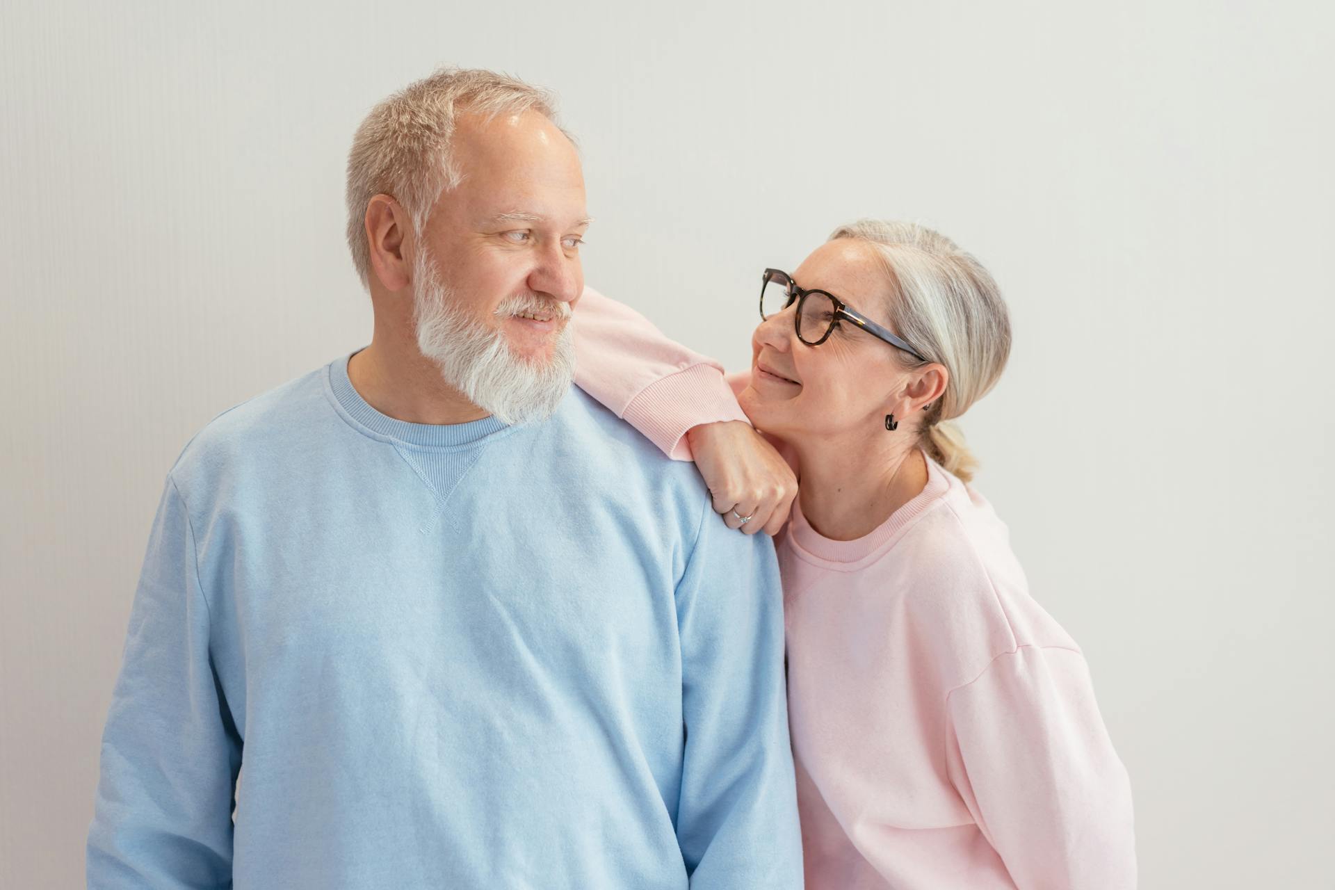 A senior couple smiling warmly at each other in a bright indoors setting.