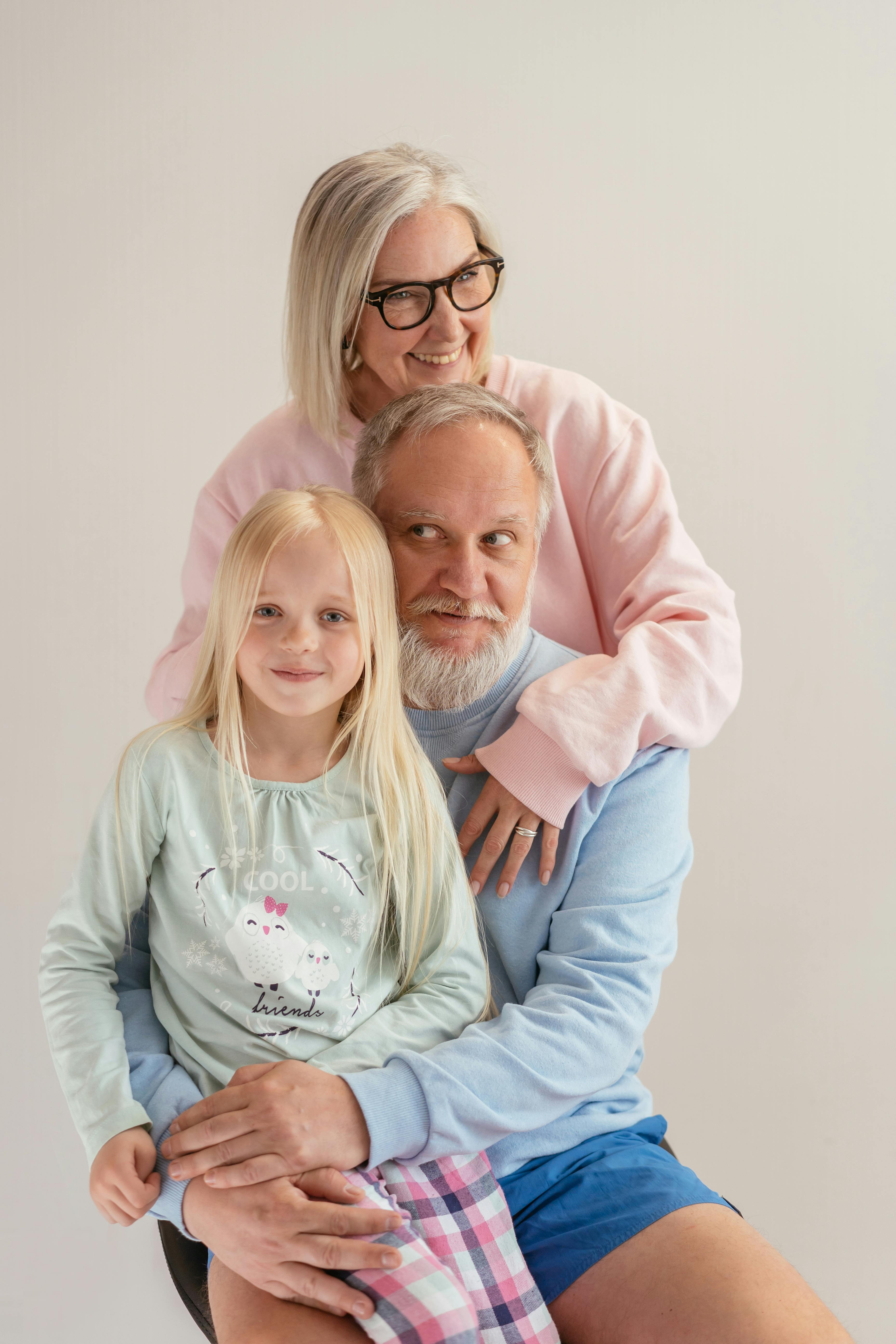 an elderly couple embracing their granddaughter