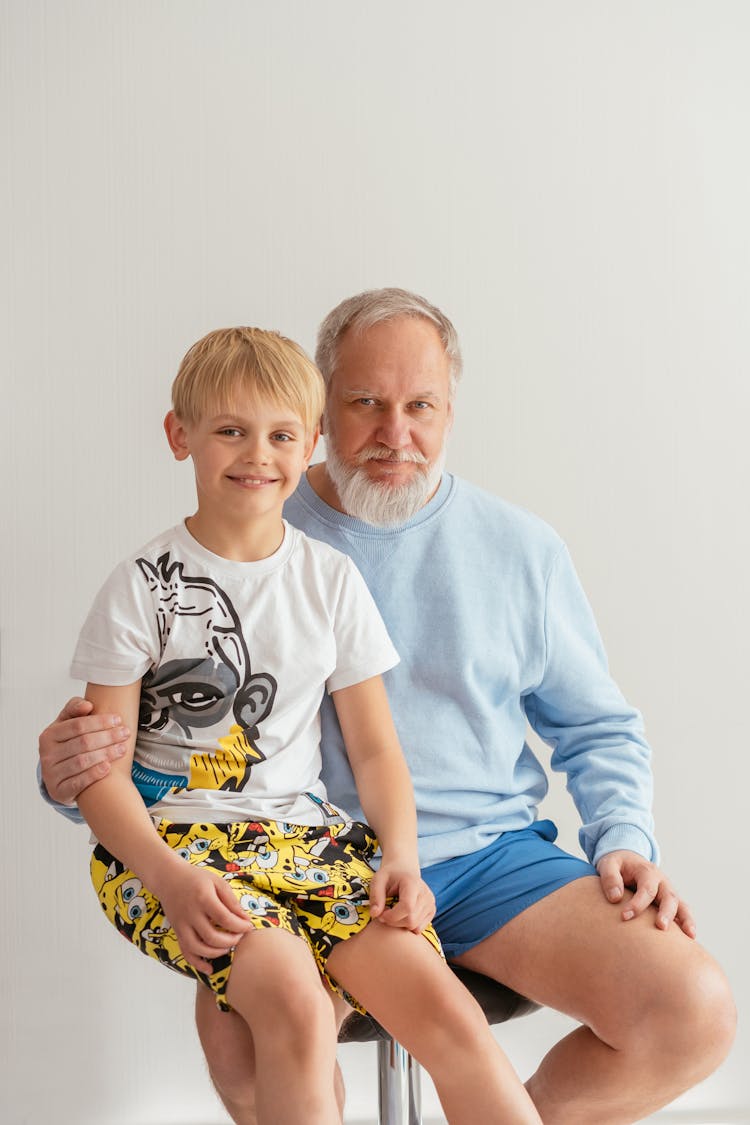 A Young Boy Smiling While Sitting On His Grandfather's Lap