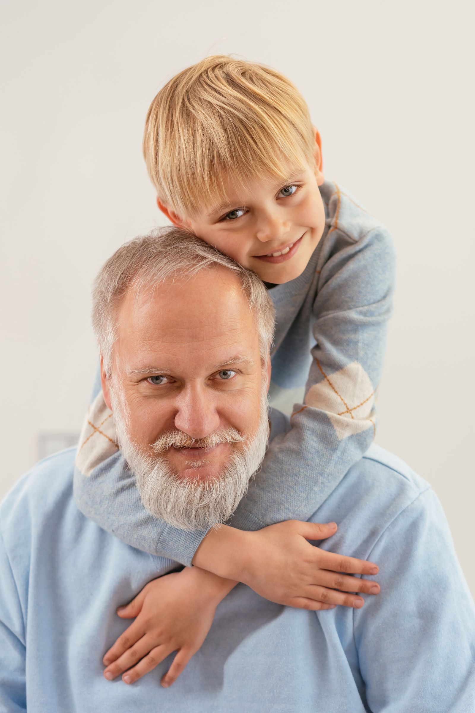Smiling grandfather with his grandson hugging him from behind